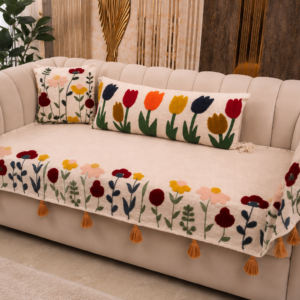 Designer embroidered sofa cover with colorful floral patterns and tassel edges draped over a modern beige curved sofa in a luxury living room.
